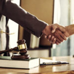 Lawyers shaking hands in an office setting, symbolizing legal agreements and representation.