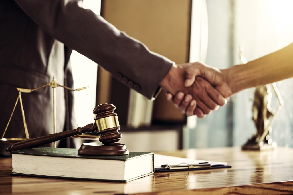 Lawyers shaking hands in an office setting, symbolizing legal agreements and representation.