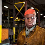 Chicago Labor Lawyer Representing Workers, an image of an African American worker in a fabrication shop wearing an orange cap, highlighting Disparti Law Group Accident & Injury Lawyers' commitment to worker rights