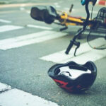 A bicycle lies damaged in a Philadelphia street crosswalk alongside a helmet, after a collision with a vehicle.