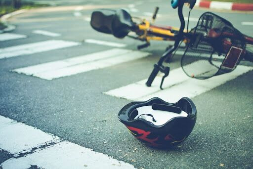 A bicycle lies damaged in a Philadelphia street crosswalk alongside a helmet, after a collision with a vehicle.