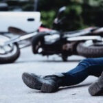 Motorcycle accident victim lying unconscious on the street, emphasizing the need for immediate legal help from the best lawyer for motorcycle accidents