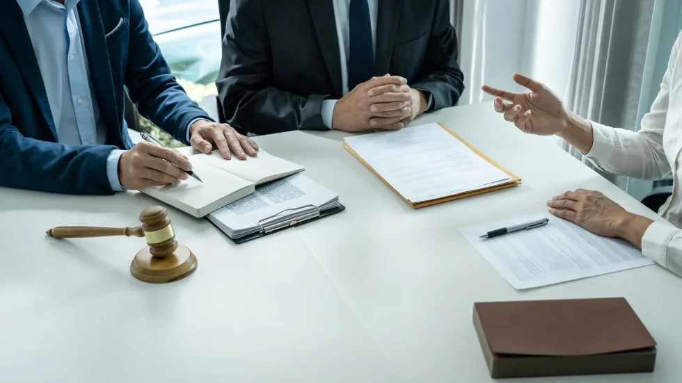 Lawyer with 2 clients discussing paperwork.