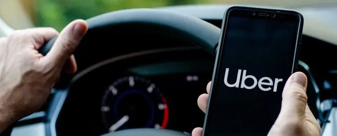 Image of a distracted Uber driver using a phone while driving in Jacksonville. Alt text: A distracted Uber driver in Jacksonville using a mobile phone, illustrating a common cause of rideshare accidents and potential liability.