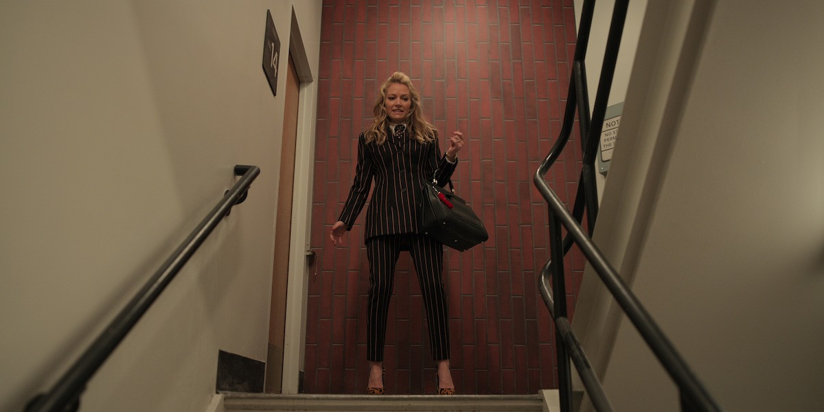 Becki Newton as Lorna Crane in ‘The Lincoln Lawyer’ Season 3, smiling confidently while wearing a power suit and Winston cufflinks.