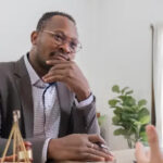 A cheerful man in a business suit sits behind a desk. An employment attorney can bring assurance that you